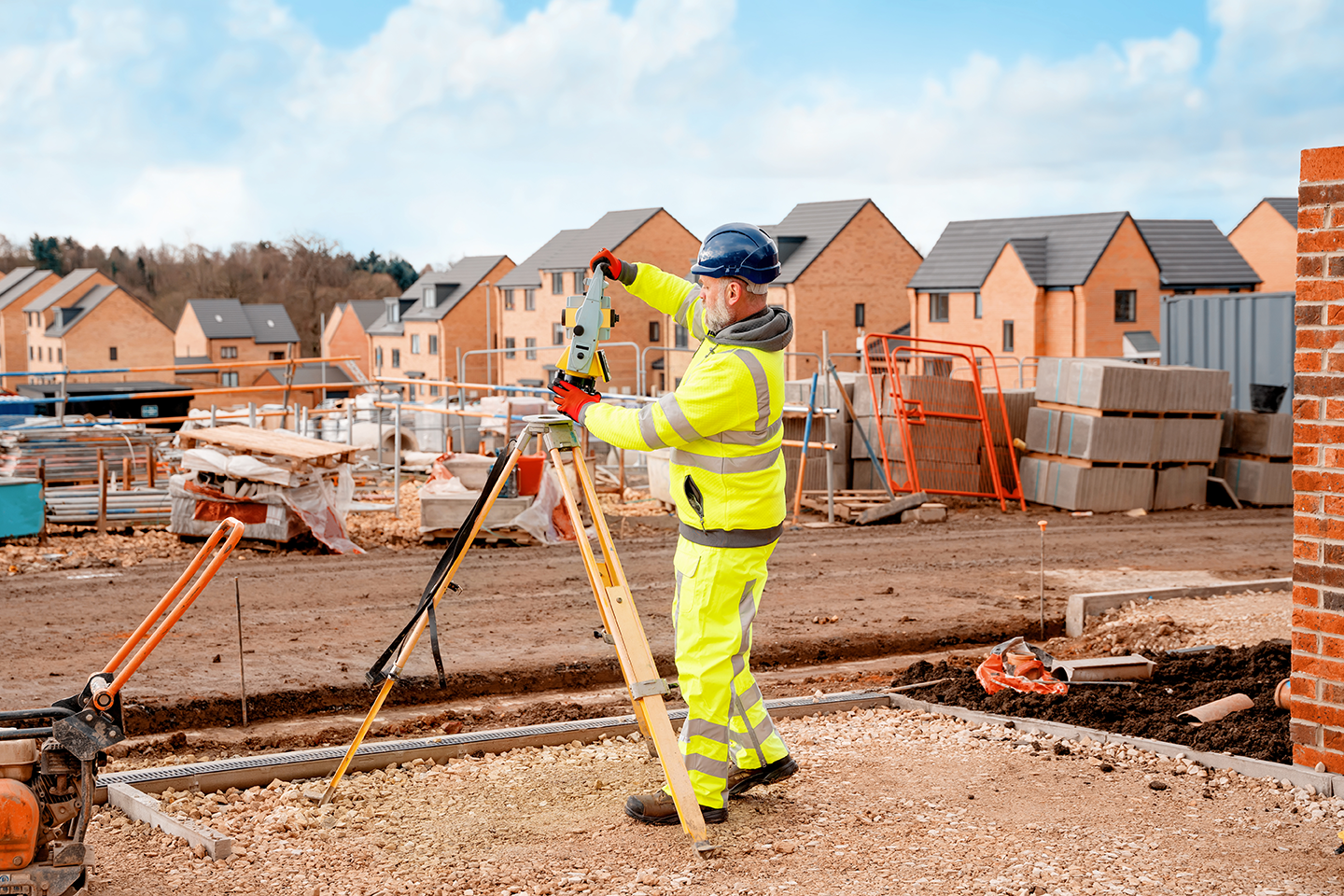 A man with surveying equipment examining a new build estate