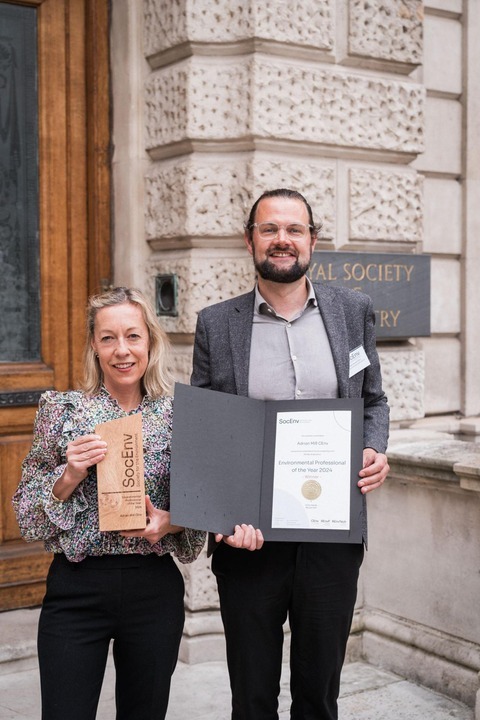 IES CEO Adam Donnan stands with a colleague of Adrian Mill's outside the Royal Society of Chemistry building. They are smiling and holding the award and certificate.
