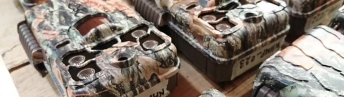 A photo of camouflage trail cameras laid out on a worktop